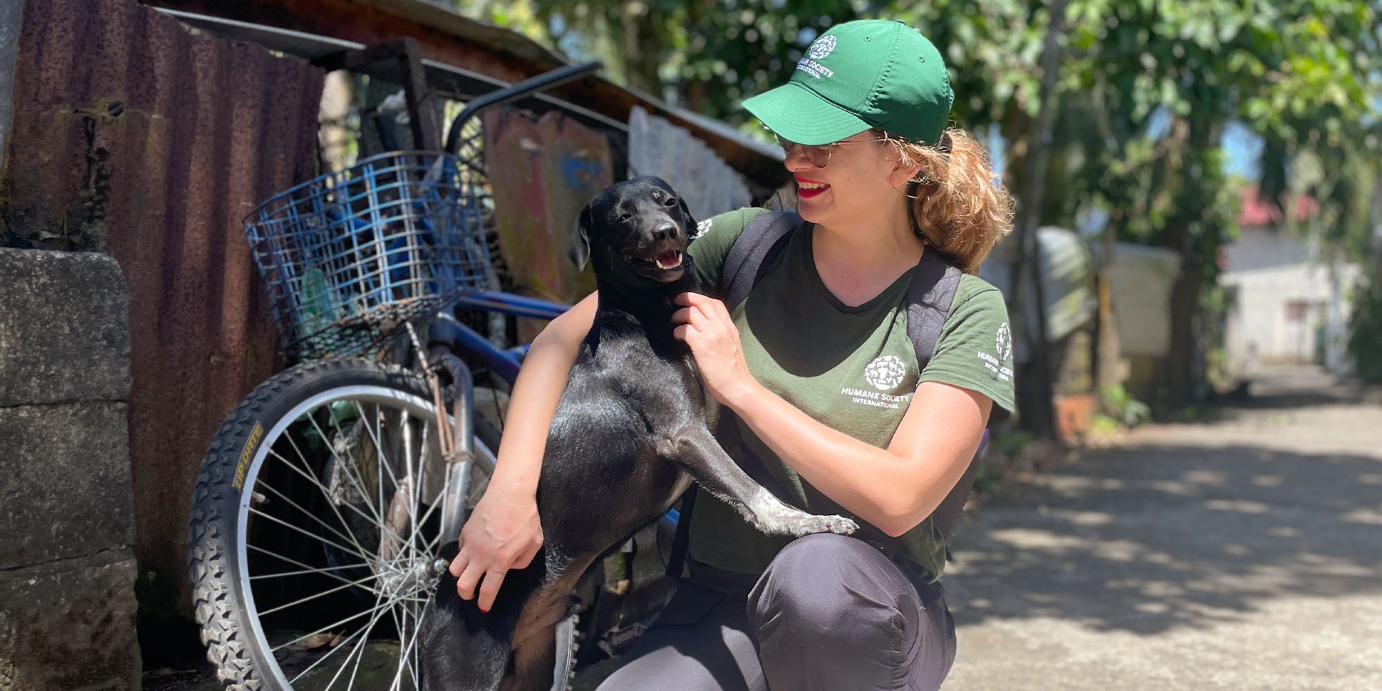 A woman who works for Humane World pets a black dog outside