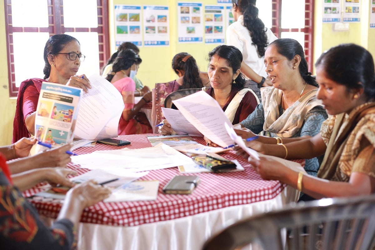 A group of women sit round a table and look at disaster preparedness resources