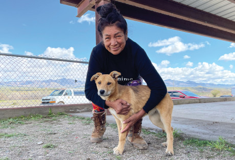 Julie Cassadore crouching next to a dog, outside. 