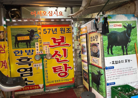 Outside of a dog meat restaurant in Seoul, South Korea, in August 2026 months before the dog meat ban goes into effect. The restaurant owner has covered his shop in signs advertising black goat meat as he prepares to stop selling dog meat.