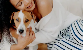 A woman hugs her dog goodbye, but he looks sad and doesn't want her to leave