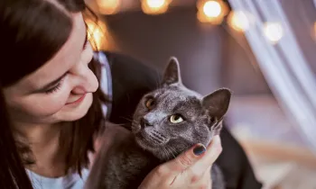A woman cuddles with her cat who is looking at her adoringly.