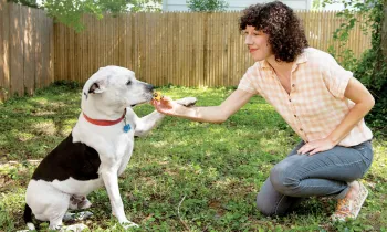 Woman outside with dog, feating him a treat