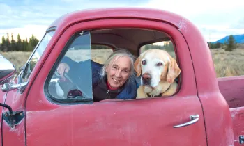 Jane Goodall in a red truck with a dog.