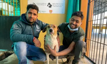 Two people pose with a dog