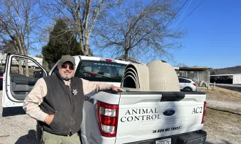 A man stands next to a truck filled with doghouses