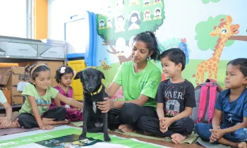 Young children sit with a dog