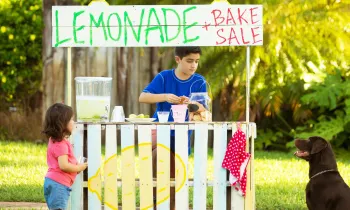 Children and dog running a lemonade stand and bake sale.