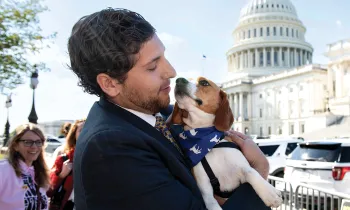 Man holding a beagle in front of the Capitol building in Washington, D.C.