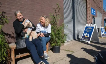 Two people laughing with small dog