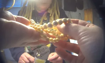 The image shows a person holding a string of ivory beads in their hands. 