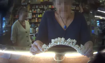 The image shows an intricately carved ivory or bone arch being held by a person. 