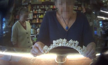 The image shows an intricately carved ivory or bone arch being held by a person. 