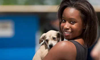 Young woman holds on to dog in line for clinic giving out shots and food