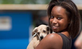 Young woman holds on to dog in line for clinic giving out shots and food