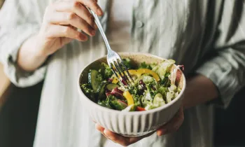Close up of a person holding a bowl filled with salad