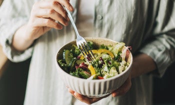 Close up of a person holding a bowl filled with salad