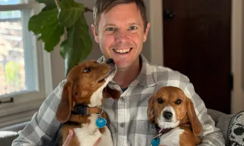 Two beagle puppies rescued from a research laboratory are held by their adoptive father