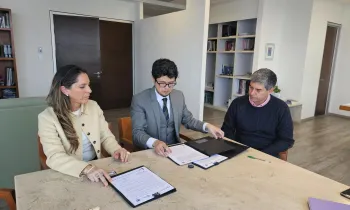 Two people signing an agreement, sitting at a table.