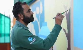 Man painting mural on wall.