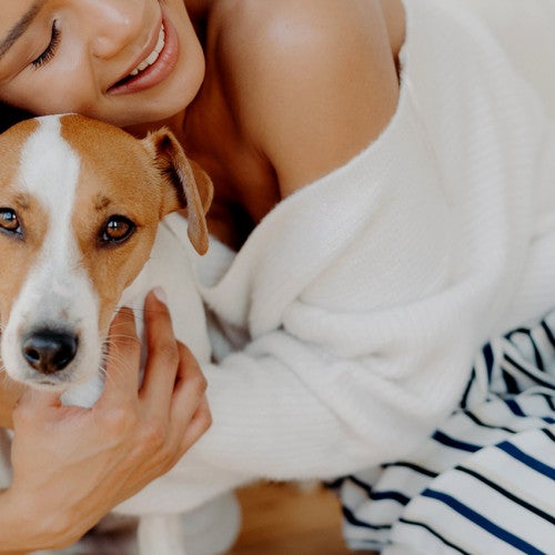 A woman hugs her dog goodbye, but he looks sad and doesn't want her to leave