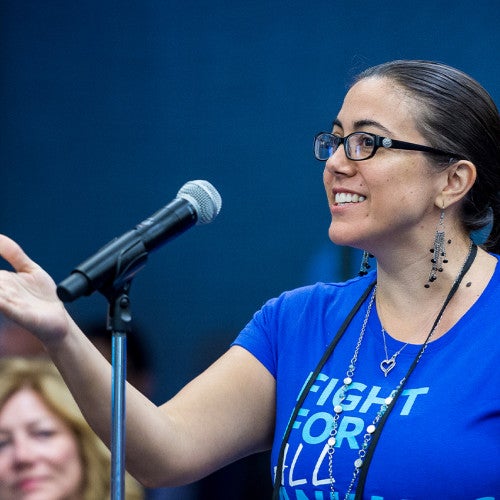 A smiling woman speaks into a microphone