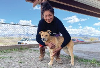 Julie Cassadore crouching next to a dog, outside.
