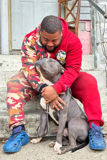 Demonte Moore sitting on steps outside with a dog