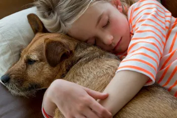 Dog and girl snuggling on the couch