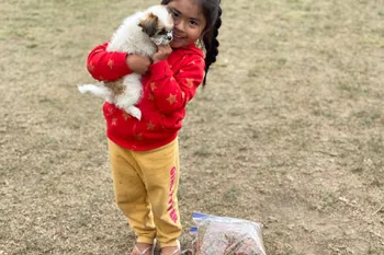 A young girl holds her puppy next to a bag of free food given by Pets for Life during their response to the COVID-19 pandemic in Granger, Washington