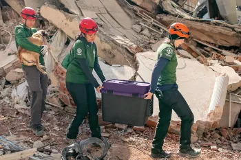 Disaster responders carry a stranded mother dog from the rubble.