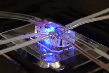 A close-up shows a microfluidic device with clear tubing connected to a transparent block 