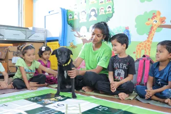 Young children sit with a dog