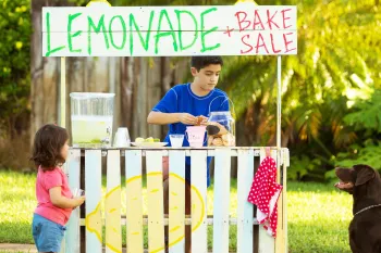 Children and dog running a lemonade stand and bake sale.