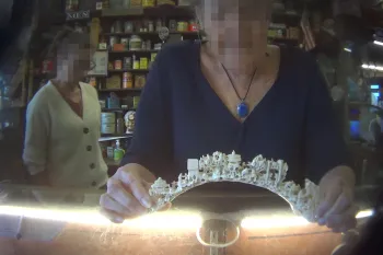 The image shows an intricately carved ivory or bone arch being held by a person. 