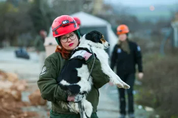 Animal rescue team member carries a dog during earthquake rescue