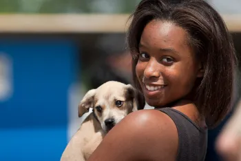 Young woman holds on to dog in line for clinic giving out shots and food