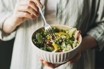Close up of a person holding a bowl filled with salad