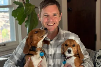Two beagle puppies rescued from a research laboratory are held by their adoptive father