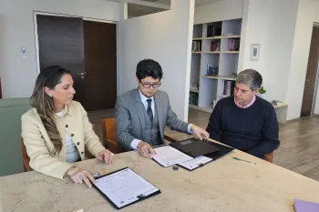 Two people signing an agreement, sitting at a table.