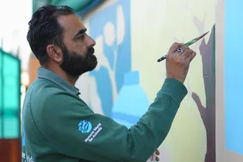 Man painting mural on wall.