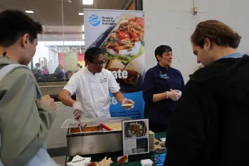 a group of people standing around a table with food on it