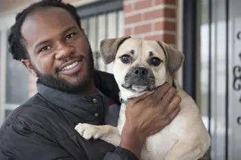 The image shows a person holding a small dog.