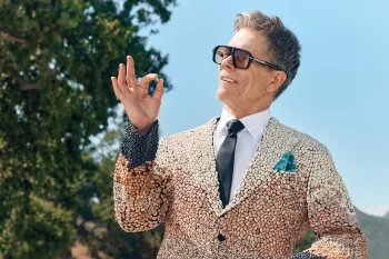 Kevin Bacon (aka Kevin Bean) holding a bean and wearing sunglasses and a suit covered in a variety of beans.