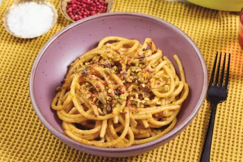 Plate of spaghetti topped with crushed pistachios.