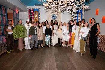 A large group of people pose together in an elegant, art-filled room.