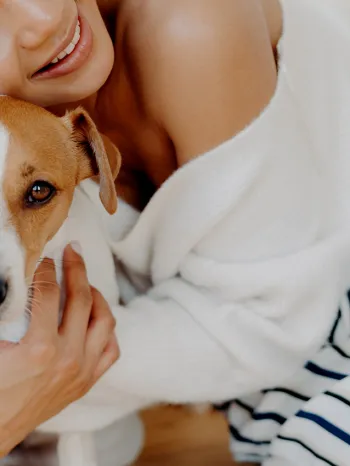 A woman hugs her dog goodbye, but he looks sad and doesn't want her to leave