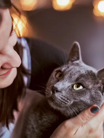 A woman cuddles with her cat who is looking at her adoringly.
