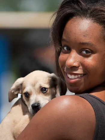 Young woman holds on to dog in line for clinic giving out shots and food