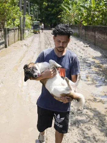 Man carrying dog in flood